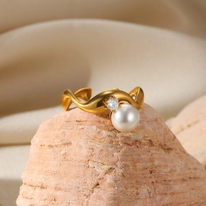 Detailed macro view of an elegant gold ring with a white pearl and sparkling clear gemstone