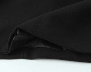 Close-up of black woolen coat fabric with smooth inner lining and fine stitching detail