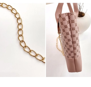 Close-up of pink heart-patterned leather bag with detailed gold metal chain strap