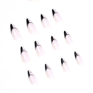 French almond press-on nails with black tips and white floral patterns on white background