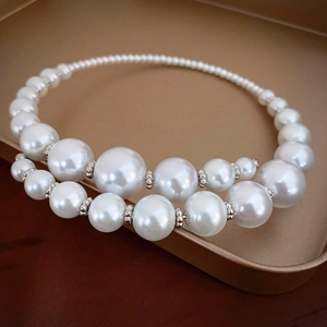 Elegant oversized faux pearl choker with silver spacers on golden display tray