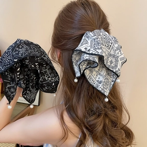 Detail of fabric bow hair claw clip with paisley pattern and pearl pendant drop