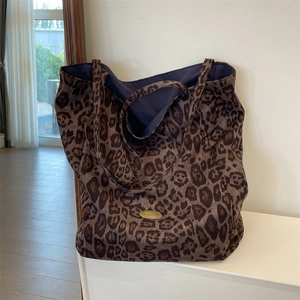 Close-up of leopard print tote bag with gold logo emblem and purple lining details