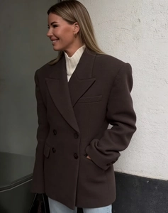 Detail of a dark brown double-breasted wool-blend blazer showing fit and drape on a model