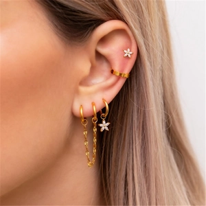 Detailed view of a gold chain earring set featuring a tiny zircon flower and ear cuffs