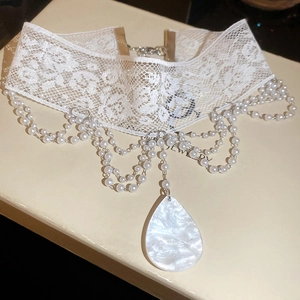 Gros plan sur un choker en dentelle blanche avec perles et pendentif goutte d'eau