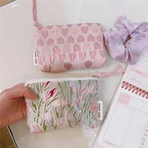 Detail of pink heart and floral jacquard mini pouches with zip and woven strap handles