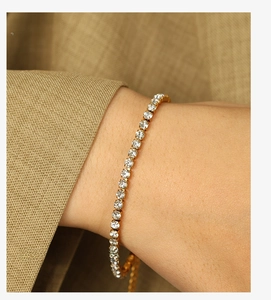 Gros plan d'un bracelet tennis doré avec zircons blancs porté par un mannequin