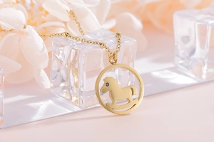 Gros plan détaillé du collier pendentif cheval à bascule doré sur fond floral