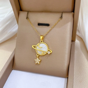 Detail of gold star and moon necklace with white shell inlay on elegant silk background