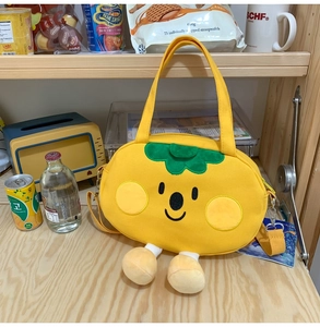 Detail view of the yellow plush persimmon bag featuring cute embroidery and green leaves