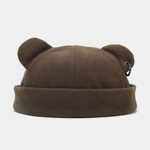 Detail of brown docker hat with bear ears and a black metal ring accessory