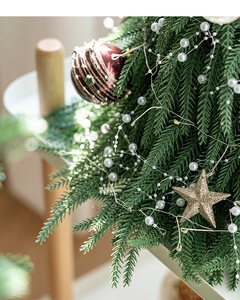 Détail de mini sapin de Noël avec lumières LED, étoiles dorées et ornements rouges