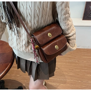 Detail of dark brown retro shoulder bag with double flaps and golden twist locks
