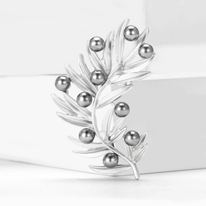 Detailed close-up of leaf-shaped silver brooch featuring elegant dark grey pearls