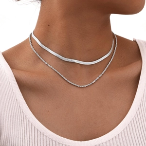 Close-up of double-layered silver snake and twisted chain necklace on model neck