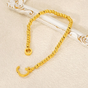 Golden stainless steel bead chain bracelet with toggle clasp on aesthetic cream background