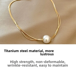 Detailed view of a layered gold snake chain necklace with a single round white pearl pendant