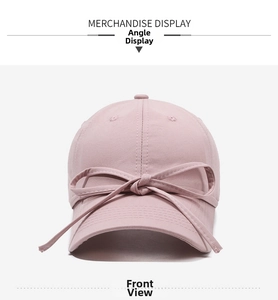 Front view of a pink baseball cap featuring a large decorative ribbon bow on the brim