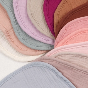 Detail view of multi-color layered cotton gauze baby bibs with soft texture and smooth edges