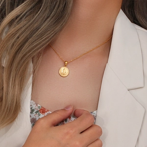 Close-up of gold stainless steel necklace featuring a round snake pattern pendant