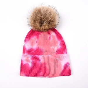 Détail du bonnet en tricot tie-dye rose avec pompon en fausse fourrure et texture