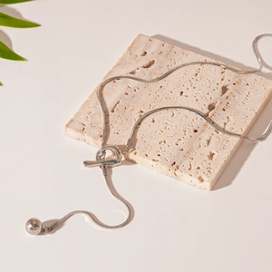 Detail of silver snake chain necklace with OT buckle and solid metal ball pendant