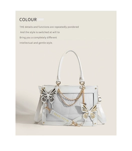 Close-up of white gothic lolita bag with metal chains and butterfly pendants details