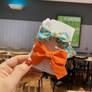 Detail of handmade floral and orange fabric bow hair clips on a display card