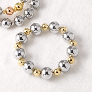 Polished two-tone beaded bracelet featuring gold and silver metal balls on white fabric