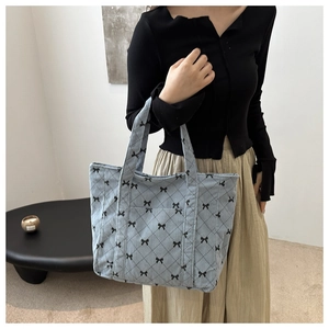 Detail of light blue corduroy tote bag with black bow pattern and quilted texture