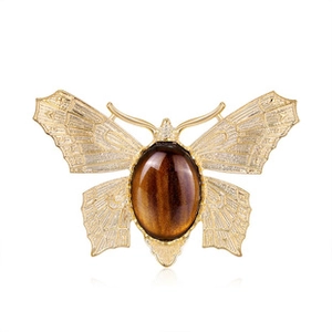 Detailed view of a golden butterfly brooch with a tiger eye stone center in macro shot