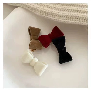 Four velvet bow hair clips in coffee, red, black, and cream colors on a white plate