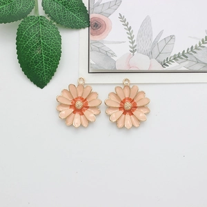 Detail shot of two pink daisy flower charms with gold edges and orange centers