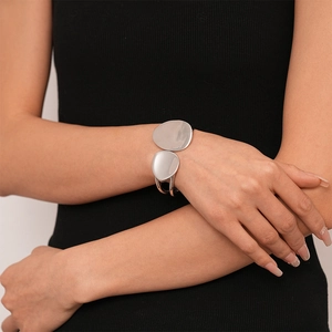 Macro detail of irregular silver geometric bangle with a polished mirror finish on wrist