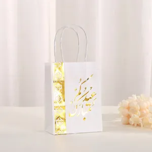 Detail of white gift bag featuring elegant gold foil Arabic script and woven handles