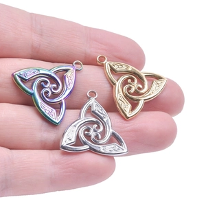 Detail of stainless steel witch knot triquetra charms in gold silver and rainbow finishes
