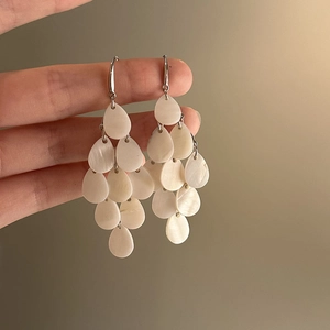 Close-up of elegant white shell teardrop tassel earrings with silver hooks for beach style
