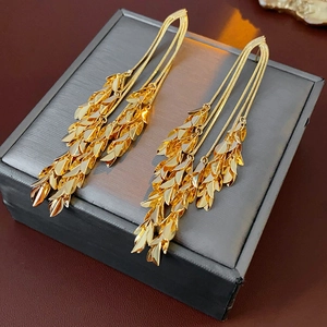 Macro shot of gold leaf tassel earrings on a textured gray jewelry box background