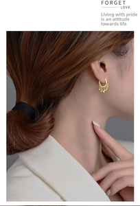 Close-up of elegant gold tassel hoop earrings with small beads on a model
