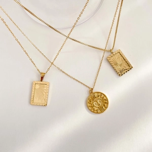 Detail of three-piece gold sun pendant necklaces featuring relief sun and cloud patterns