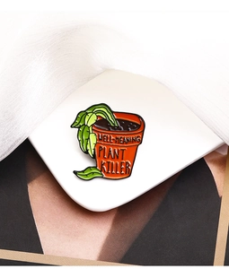 Gros plan du badge émaillé 'WELL-MEANING PLANT KILLER' sur une assiette blanche