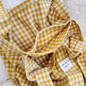 Close-up of yellow gingham fabric texture and brand label on a soft cotton shoulder bag