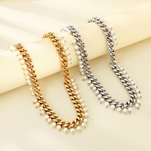 Detail view of gold and silver Cuban chain necklaces with white pearl tassels on a stand
