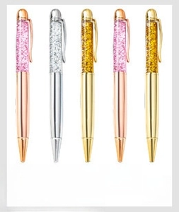 Close-up of metallic ballpoint pens with glitter crystals and polished metal clips