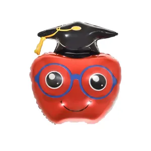 Close-up of a red apple foil balloon with a black graduation cap and glasses for party decor