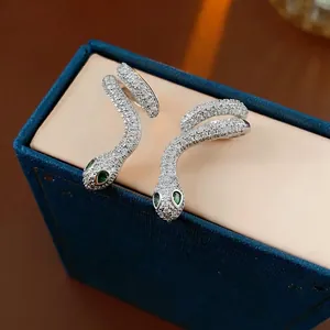 Silver snake earrings with pavé white zircons and green gemstone eyes in a jewelry box