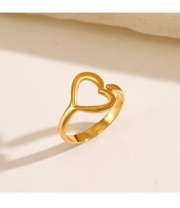 Detailed view of hollow heart ring in golden finish on a warm minimalist background