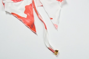Close-up of red printed strapless top with delicate gold metal aglets on ties