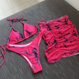 Flat lay detail of neon pink tie-dye three-piece bikini set with matching mini sarong skirt
